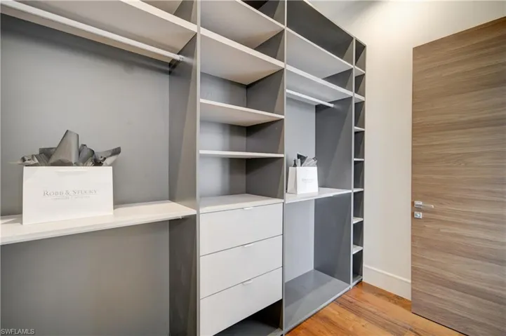 Walk in closet with light hardwood / wood-style flooring