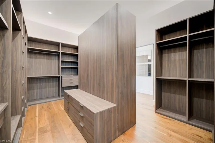Walk in closet with light hardwood / wood-style floors