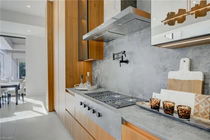 Kitchen with gas stovetop, wall chimney range hood, and backsplash