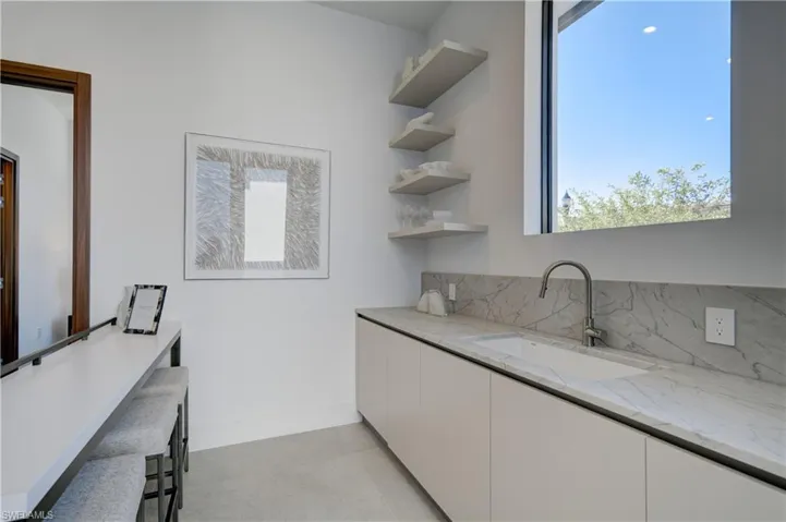 Kitchen featuring light stone countertops, sink, and white cabinets