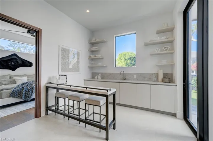Kitchen with a kitchen breakfast bar, white cabinetry, sink, and light wood-type flooring
