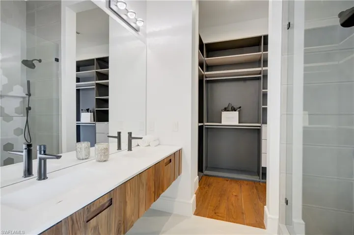 Bathroom featuring wood-type flooring, vanity, and a tile shower