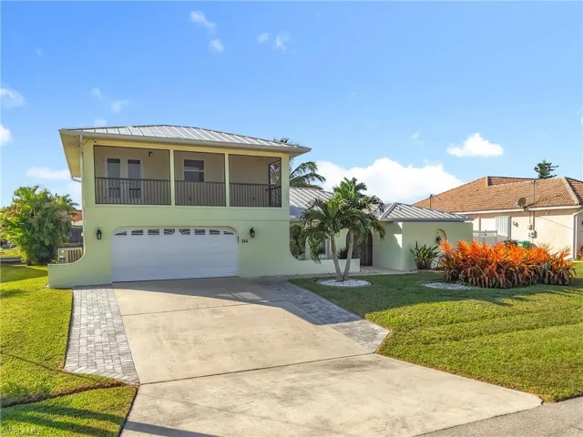 View of front facade with stucco siding, a front lawn, concrete driveway, and an attached garage