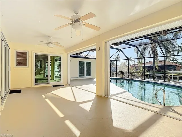 Outdoor pool featuring ceiling fan, a patio, a sunroom, and glass enclosure