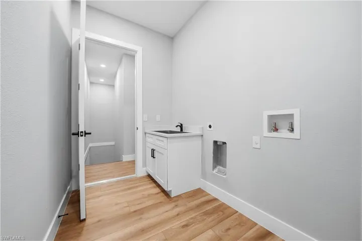 Laundry area featuring light wood-type flooring, washer hookup, hookup for an electric dryer, cabinet space, and recessed lighting