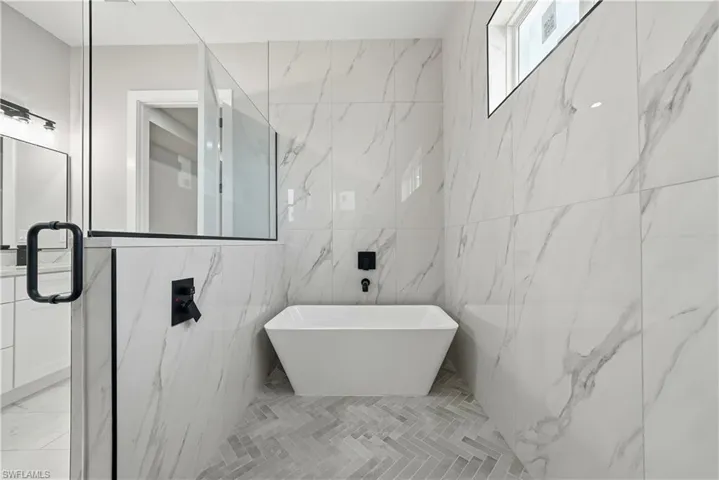 Full bathroom with tile walls and a soaking tub