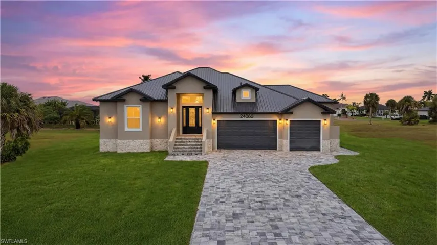 Modern farmhouse with a yard, a garage, decorative driveway, and a metal roof