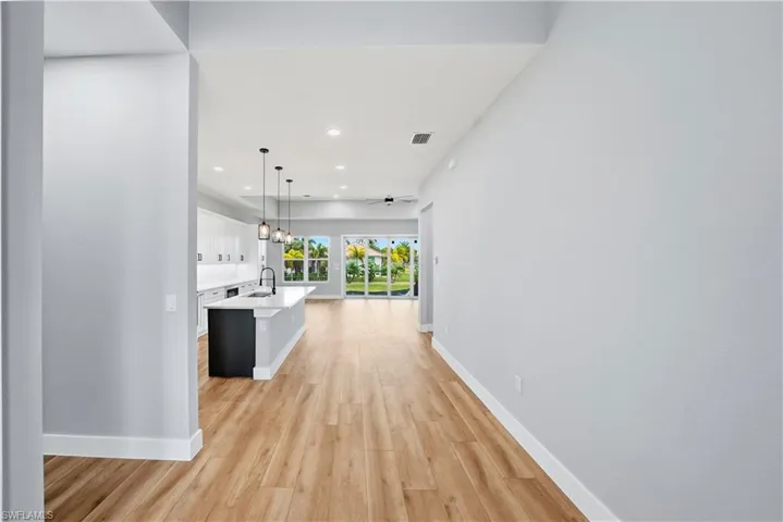 Hallway featuring light wood finished floors and hanging lights