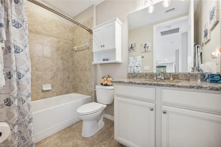 Full bathroom with tile floors, shower / tub combo, vanity, and toilet