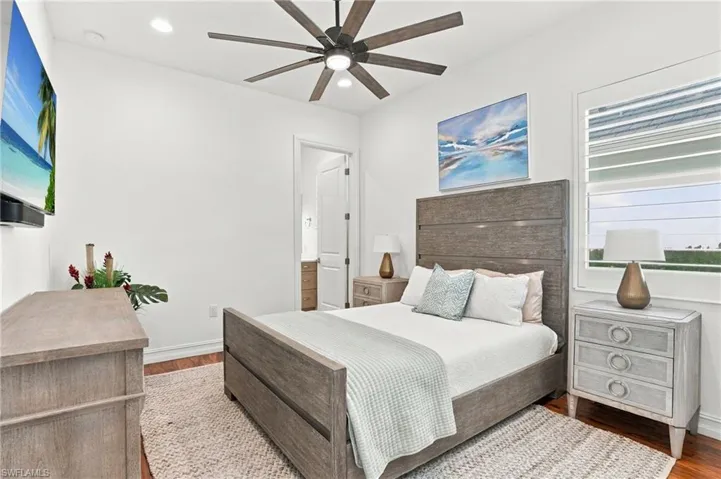Bedroom featuring wood-finish flooring, a multi-blade ceiling fan with integrated lighting, recessed lighting, and windows equipped with plantation-style shutters