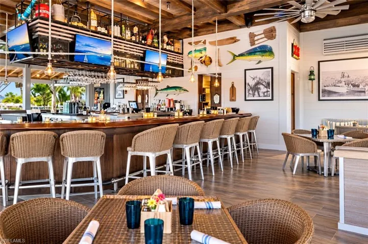 Expansive bar area featuring a polished wood countertop, exposed wood-beam ceiling, wood-finish flooring, and industrial-style hanging pendant lighting