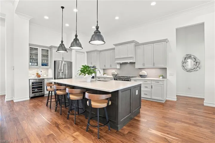 Kitchen featuring a central island with a stone countertop, cabinetry with glass-front uppers, stainless steel built-in appliances, recessed lighting, and wood-finish flooring