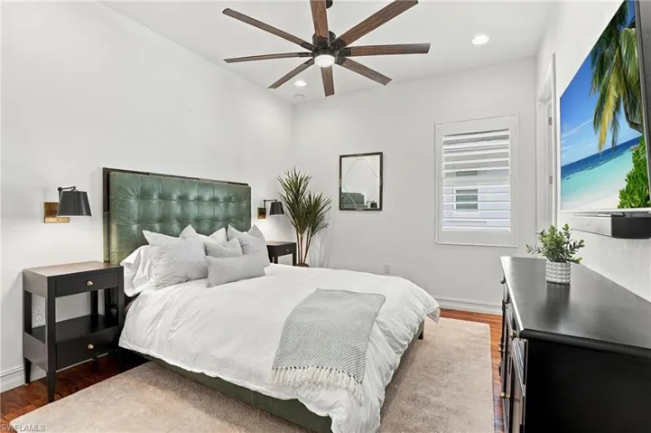 Recessed lighting, ceiling fan with integrated light, wood-finish flooring, and window featuring plantation shutters