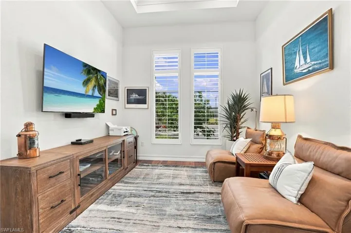 High ceilings with recessed tray lighting, dual tall windows featuring white plantation shutters, and wood-finish flooring
