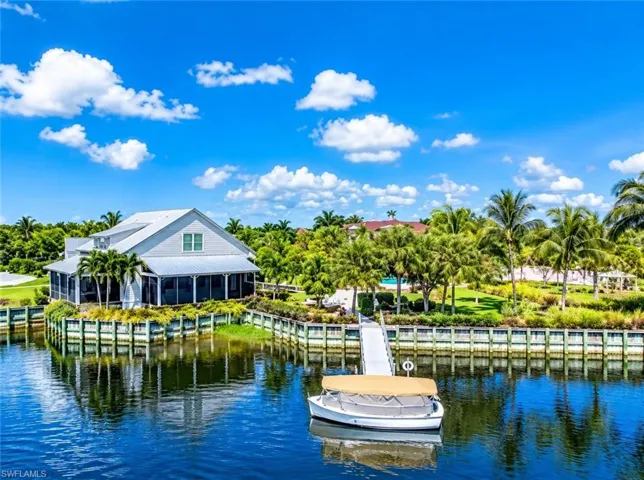 Waterfront property featuring a private boat dock, vinyl bulkhead, screen-enclosed porch, and expansive landscaped grounds