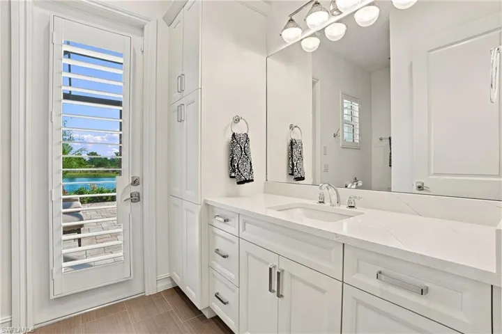Vanity featuring white shaker-style cabinetry, quartz countertop with an integrated basin, and polished chrome hardware