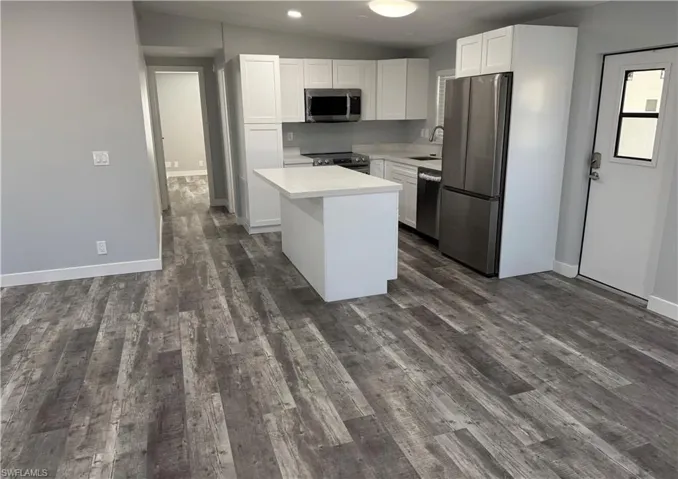 Kitchen featuring white cabinets, a center island, lofted ceiling, stainless steel appliances, and sink