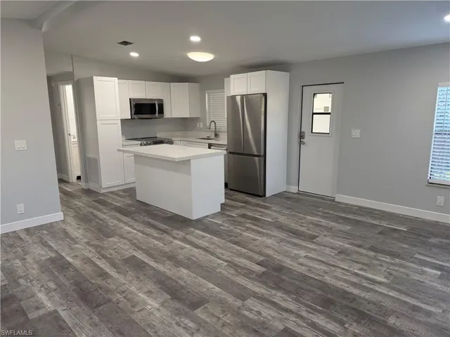 Kitchen featuring stainless steel appliances, a center island, dark hardwood / wood-style flooring, white cabinets, and sink