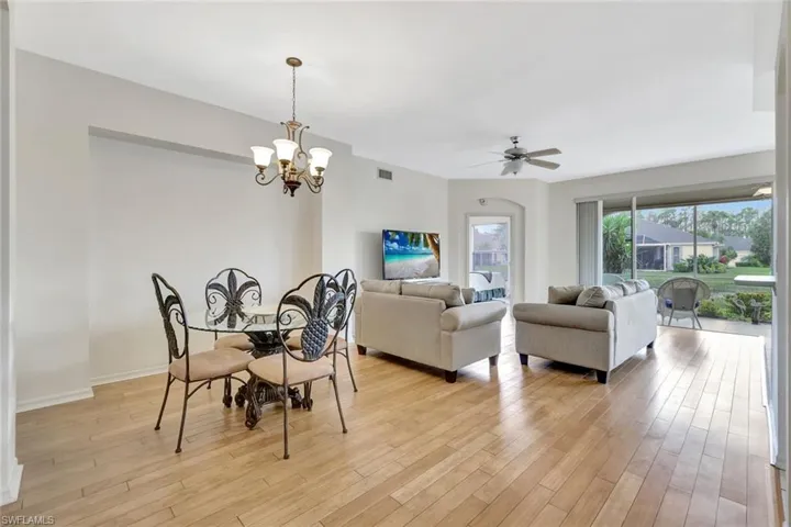 Dining area with light wood-style floors, baseboards, visible vents, and ceiling fan with notable chandelier