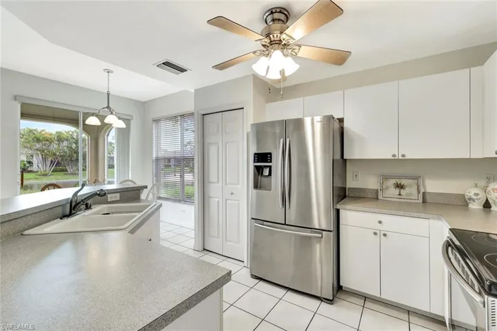 Kitchen with a sink, visible vents, white cabinets, appliances with stainless steel finishes, and pendant lighting