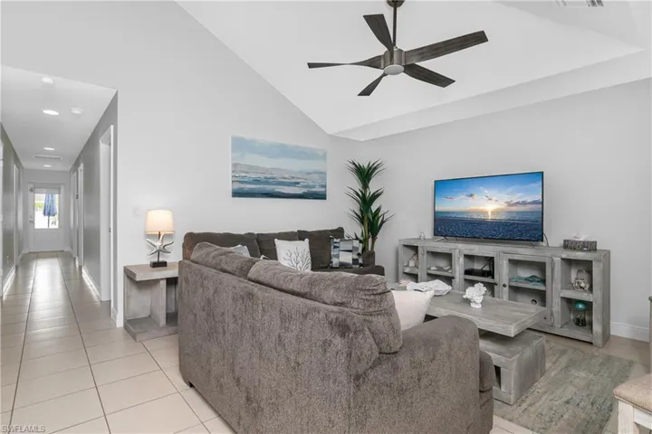 Tiled living room featuring high vaulted ceiling and ceiling fan