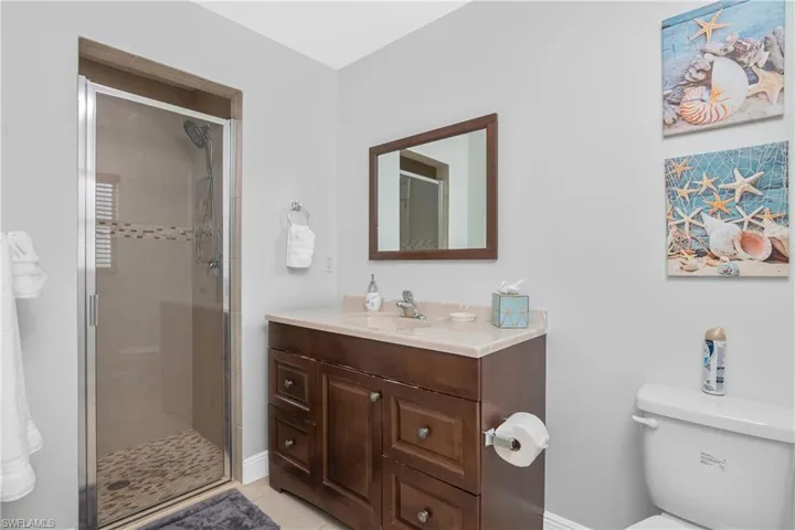 Bathroom featuring vanity, toilet, an enclosed shower, and tile patterned flooring