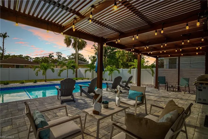 Patio terrace at dusk with area for grilling, a fenced in pool, and a pergola