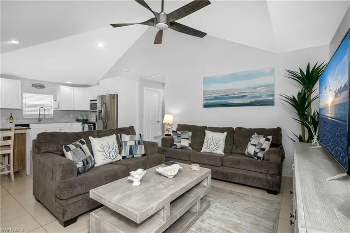 Living room featuring ceiling fan, sink, light tile patterned floors, and high vaulted ceiling