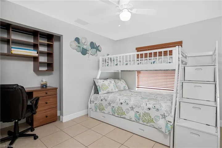 Tiled bedroom featuring ceiling fan