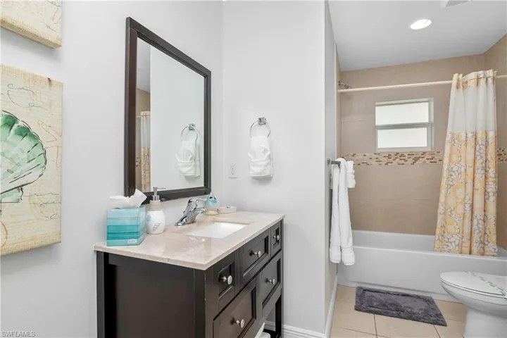Full bathroom with vanity, toilet, tile patterned floors, and shower / bathtub combination with curtain