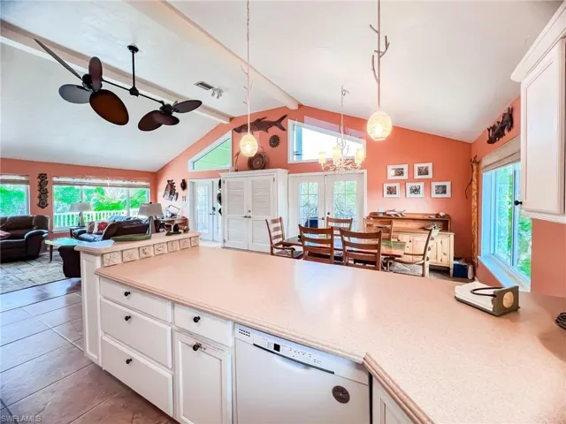 Kitchen with dishwasher, french doors, hanging light fixtures, vaulted ceiling with beams, and white cabinets
