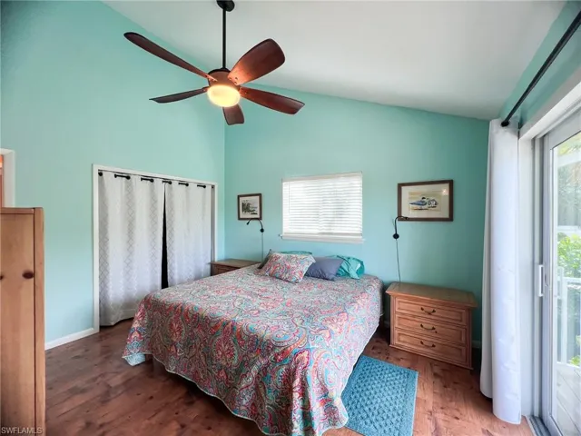 Bedroom featuring multiple windows, wood-type flooring, vaulted ceiling, and ceiling fan