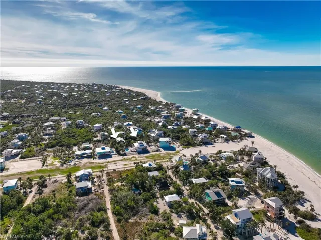 Birds eye view of property featuring a water view and a view of the beach