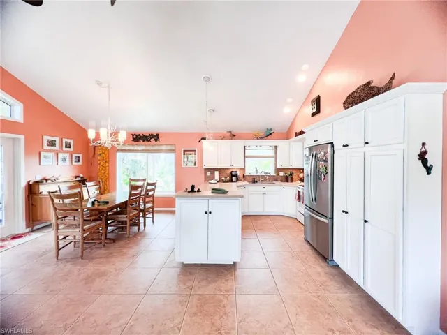 Kitchen featuring a kitchen island, decorative light fixtures, white cabinetry, a chandelier, and stainless steel refrigerator
