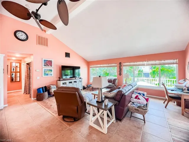 Living room with ceiling fan, beamed ceiling, light tile patterned floors, and high vaulted ceiling