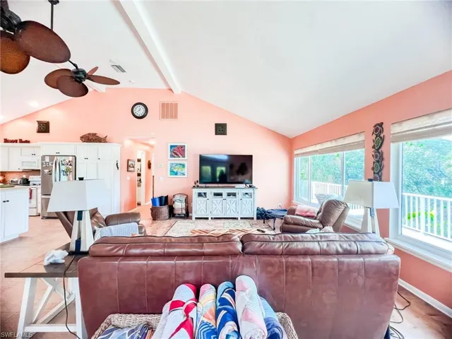Living room with ceiling fan, a healthy amount of sunlight, light hardwood / wood-style floors, and lofted ceiling with beams