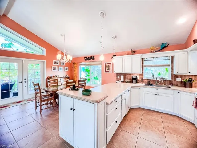 Kitchen with backsplash, decorative light fixtures, sink, and vaulted ceiling