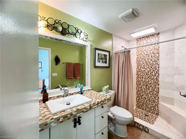 Bathroom with toilet, curtained shower, and sink
