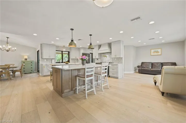 Kitchen featuring custom exhaust hood, light wood-style flooring, a center island, light countertops, and recessed lighting