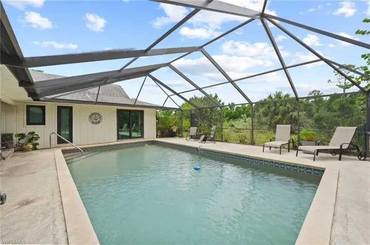 Outdoor pool with a patio and glass enclosure