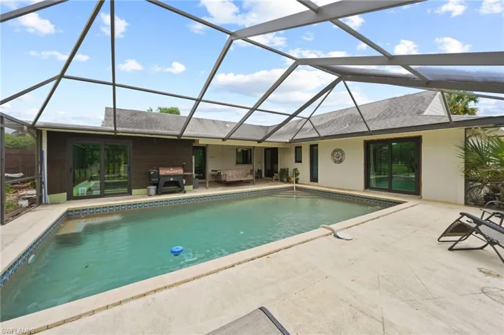 Outdoor pool with a patio area, area for grilling, a lanai, and an outdoor living space