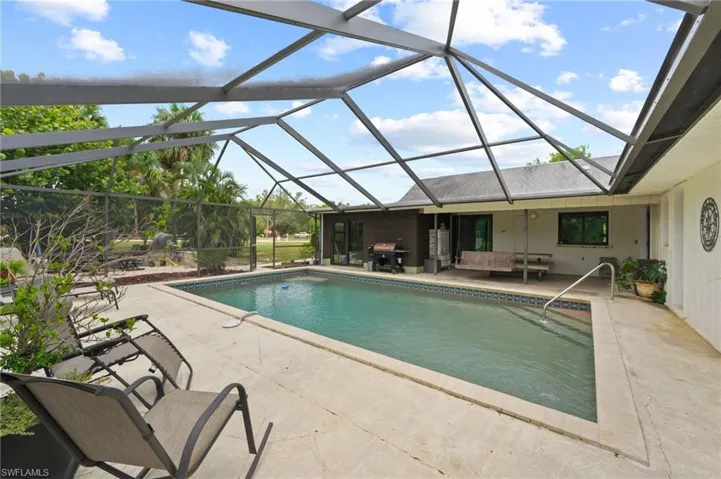 Swimming pool featuring a patio, area for grilling, an outdoor living space, and a lanai