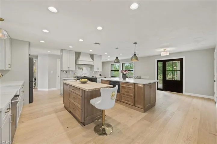 Kitchen featuring a large island, premium range hood, appliances with stainless steel finishes, backsplash, and recessed lighting