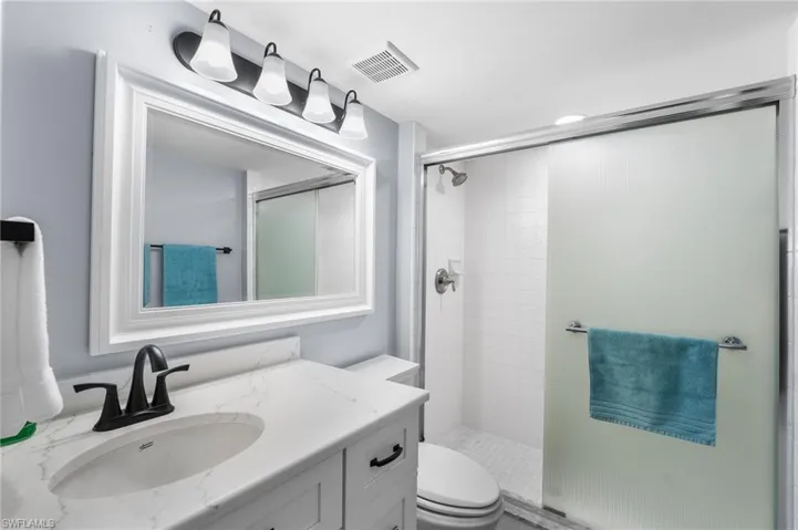 Bathroom featuring vanity, a shower with shower door, and toilet