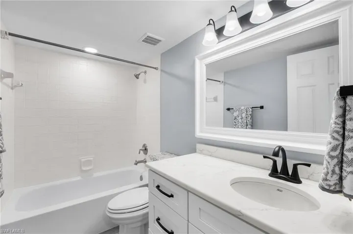 Full bathroom featuring tiled shower / bath, vanity, and toilet