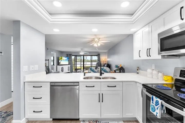 Kitchen featuring stainless steel appliances, sink, white cabinets, and kitchen peninsula