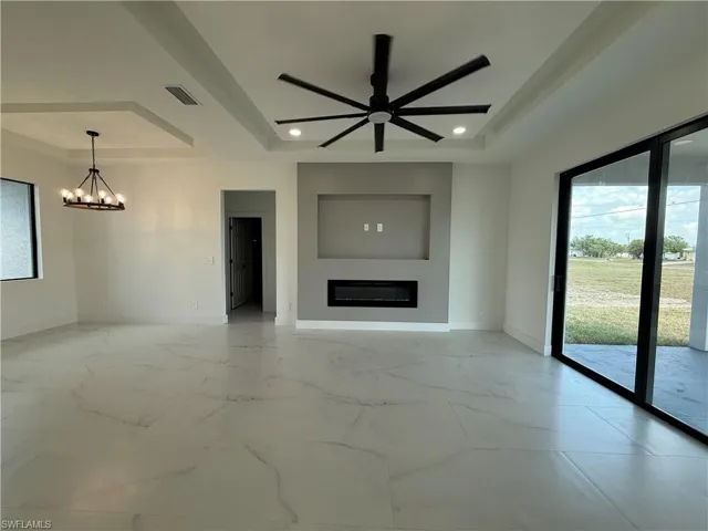 Unfurnished living room featuring visible vents, baseboards, and a raised ceiling