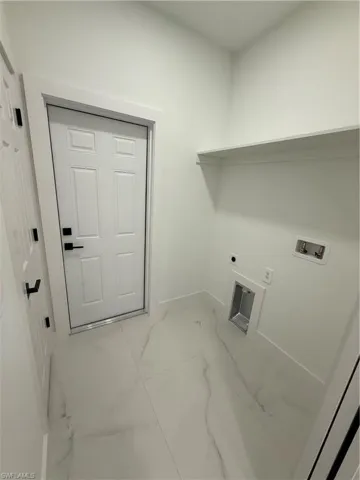 Clothes washing area featuring laundry area, electric dryer hookup, marble finish floor, washer hookup, and baseboards
