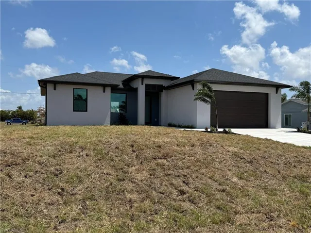 Prairie-style house with a garage, stucco siding, concrete driveway, and a front lawn