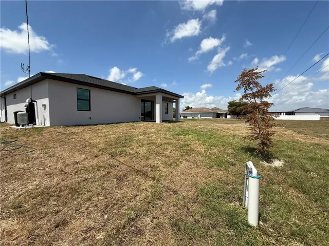 Back of property featuring a lawn and stucco siding
